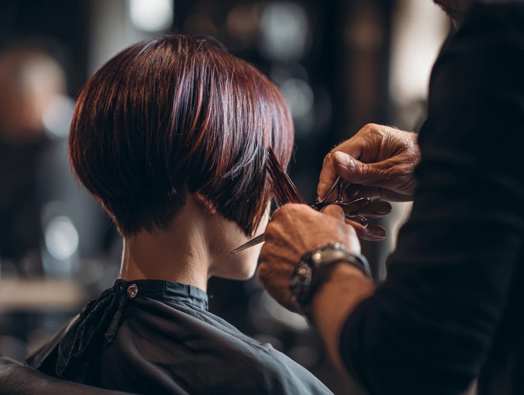 Stylist finishing a creative haircut in salon